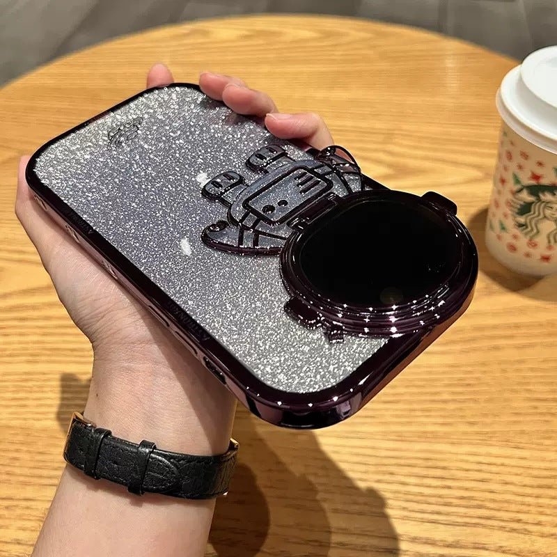 Coque astronaute 3D tenue à la main sur une table en bois, avec un café à côté.
