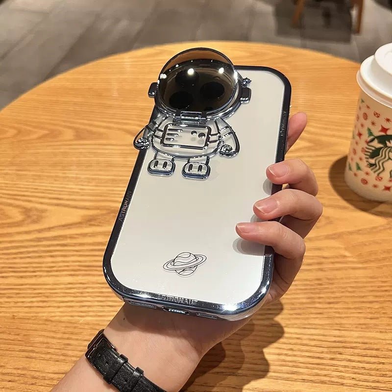 Coque astronaute 3D tenant dans une main sur une table en bois, avec un gobelet Starbucks en arrière-plan.