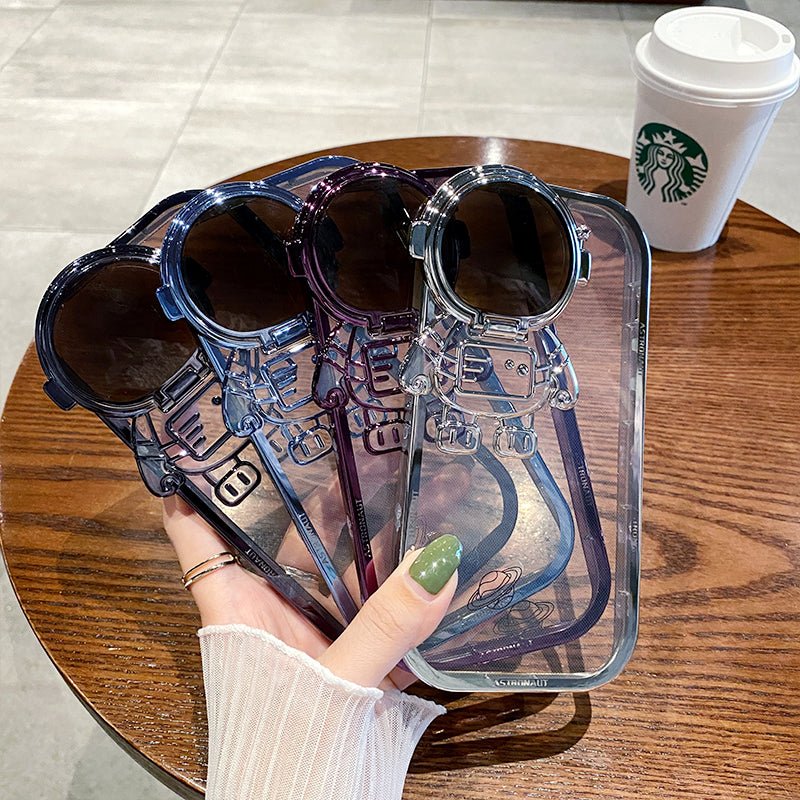 Coque astronaute 3D en plusieurs couleurs, design tendance à côté d'une tasse de café Starbucks.